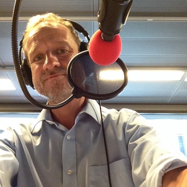 David Baker smiling at the camera behind a microphone in a radio studio