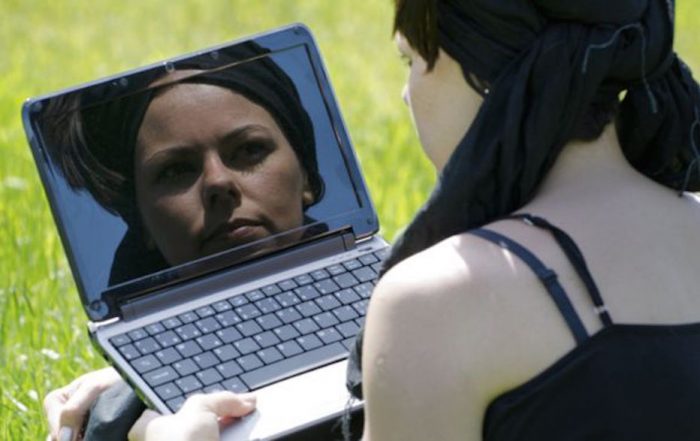 A woman looking at her reflection in a computer screen