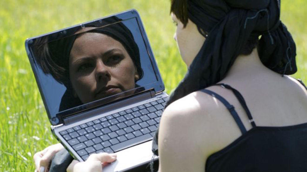 A woman looking at her reflection in a computer screen