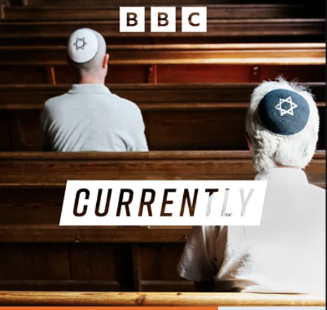 Two Jewish men wearing kippot sitting in a synagogue